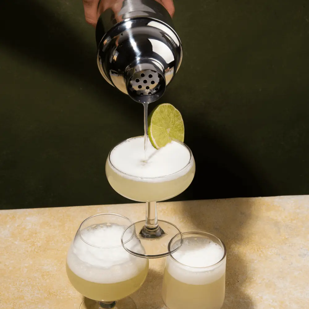 Het uitschenken van een Daiquiri cocktail in een toren glazen
