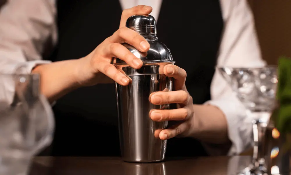 Een bartender die een dichte cocktailshaker voor zich houdt op de bartafel